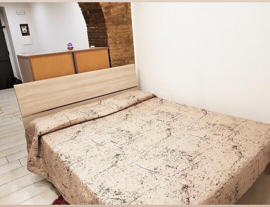 Een slaapkamer met een bed, een houten dressoir en een bakstenen muur.
