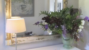 Un tocador de baño con espejo, una lámpara y un florero.