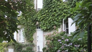 Un edificio con camino de grava, una puerta blanca y una escalera que lleva a otra puerta blanca.