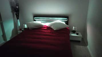 Una camera da letto con un letto, cuscini, un comodino e una lampada a parete.