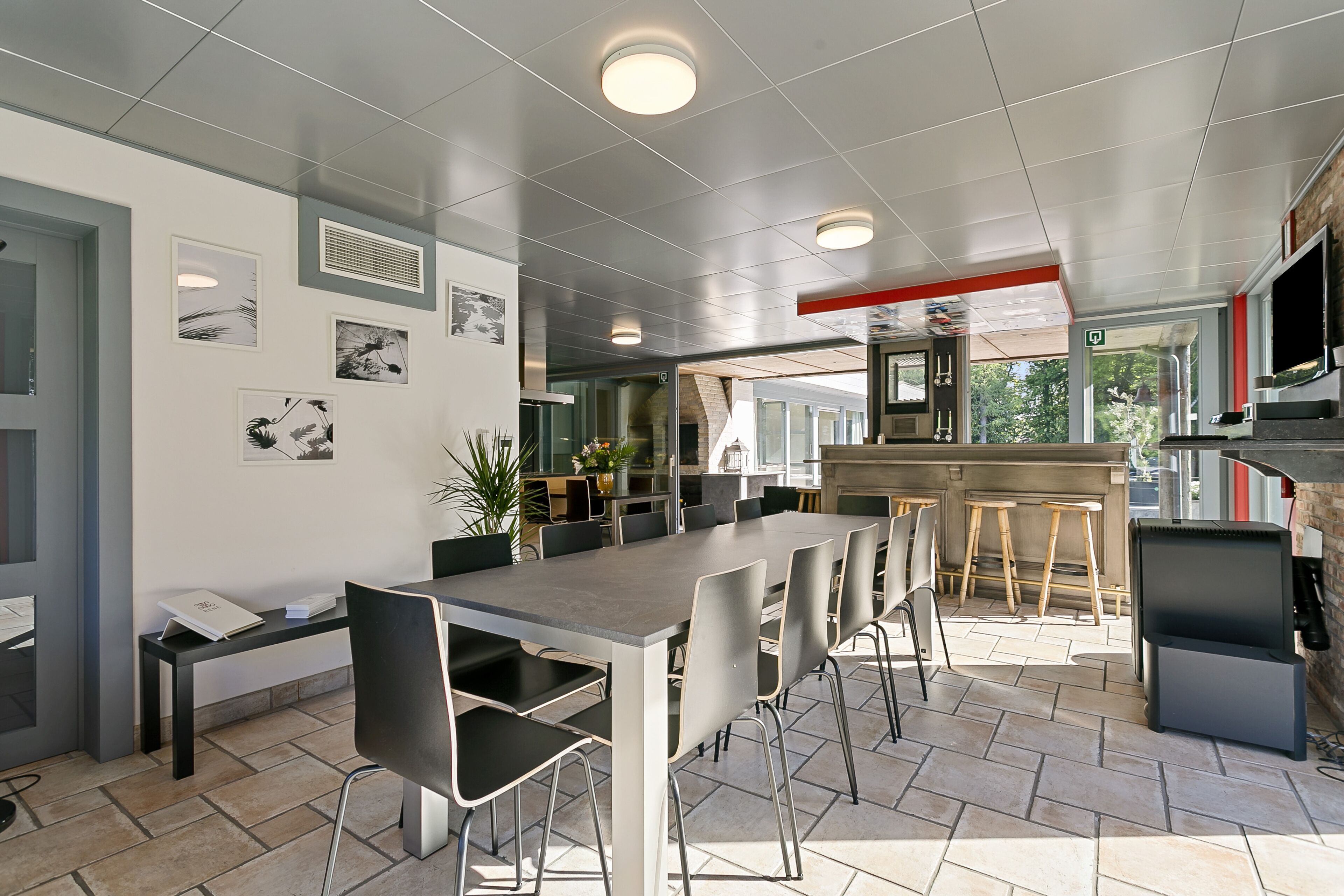 A modern dining area with a long table, chairs, and a bar area with a grill.