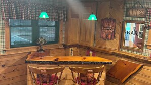 Ein gemütliches Holzinterieur mit Barbereich, zwei Barhocker und einer Holztresen.