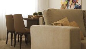 A living room with a beige sofa, two matching armchairs, a small table with a plant, and a colorful artwork on the wall. - Nightingale Apartments (Porto)