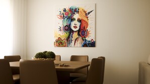 A dining area with a table and chairs, a potted plant, and a colorful artwork on the wall. - Nightingale Apartments (Porto)