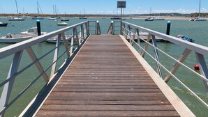 Une jetée en bois menant à une marina où sont amarrés des bateaux.