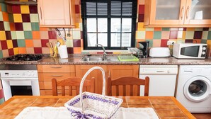 Une cuisine équipée d’un four à micro-ondes, d’un grille-pain, d’un évier et d’un lave-linge.