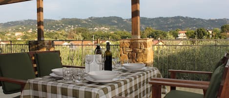 Un espace de restauration en plein air avec une table dressée pour deux personnes, offrant une vue panoramique sur une colline pittoresque.
