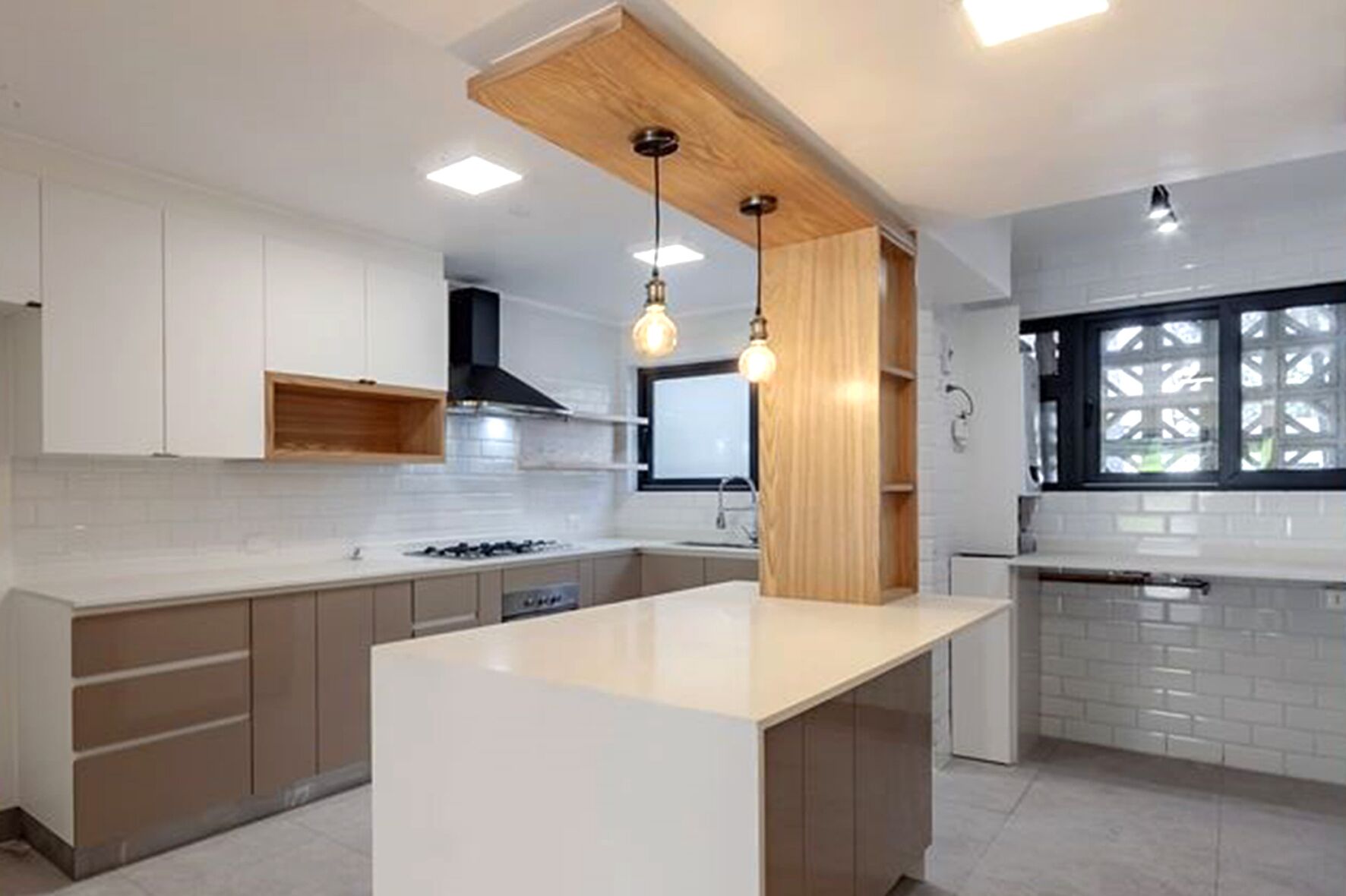 A modern kitchen with white cabinets, a central island, pendant lighting, and a window with a view.