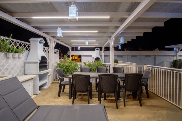 Een terras buiten met een eettafel, stoelen en een barbecue.