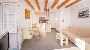Un salon moderne comprenant un canapé, une table à manger avec des chaises, un coin cuisine avec un four à micro-ondes et un téléviseur.