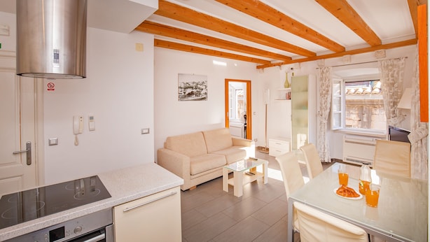Une cuisine moderne équipée d’une cuisinière, un coin repas avec une table et des chaises, un canapé et une fenêtre avec des rideaux.