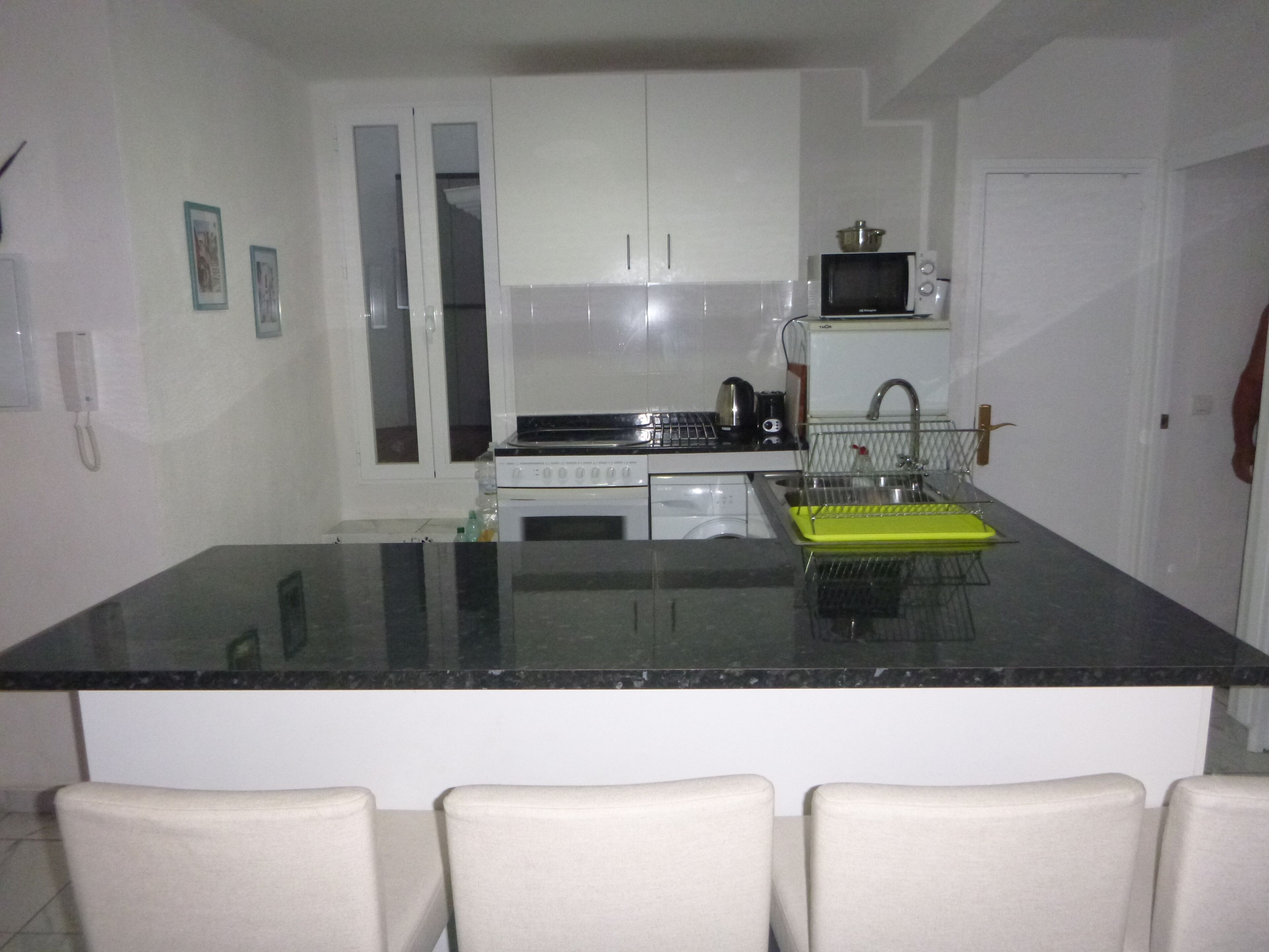 A modern kitchen with white cabinets, a black countertop, and a built-in microwave.