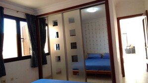 A bedroom with a bed, a wardrobe with mirrors, and a window with curtains.
