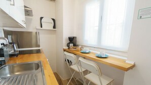 A kitchen with a stainless steel sink, a coffee maker, and a window with blinds. - RentalSevilla Enladrillada Center City (Sevilla)