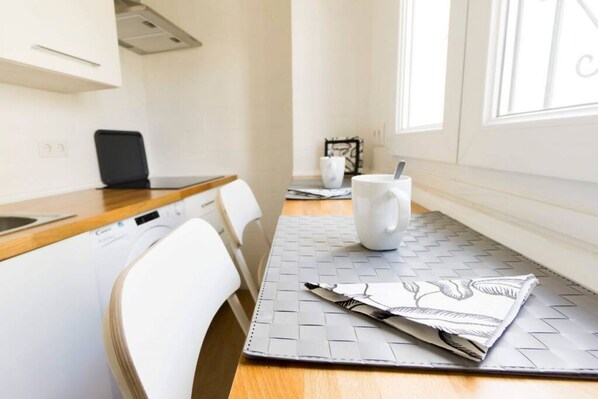 A modern kitchen with white cabinetry, a wooden countertop, and a window providing natural light. - RentalSevilla Enladrillada Center City (Sevilla)