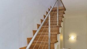 Eine Holztreppe mit Metallgeländern und einer Wandleuchte.