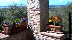 Ein steinerner Brunnen mit Blumenkästen an den Seiten, vor einer malerischen Kulisse.