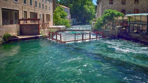 Ein Fluss fließt durch eine Stadt, gesäumt von Gebäuden aus Stein.
