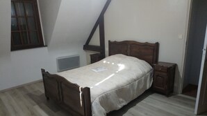 A bedroom with a wooden bed, a nightstand, a window, and a door. - Very quiet family holiday home (Isigny-le-Buat)