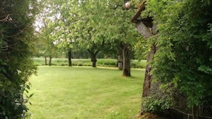 A grassy area with trees and a stone wall. - Very quiet family holiday home (Isigny-le-Buat)