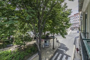 Gadesyn med en pavillon, træer og en bygning med balkon.