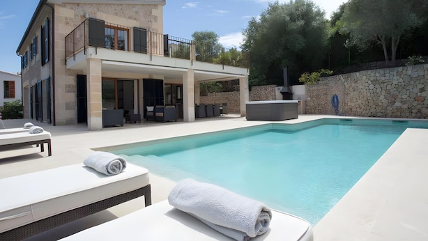 Ein modernes Haus mit zwei Etagen, einem Swimmingpool, Sitzgelegenheiten im Freien und einer Steinsäule.