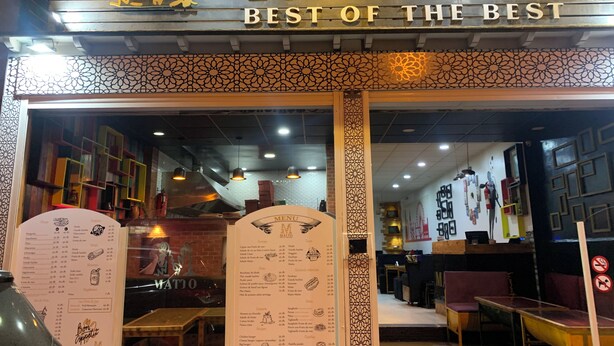 L’entrée d’un restaurant appelé « Matto », avec un panneau affichant le menu et une enseigne décorative au-dessus de l’entrée.
