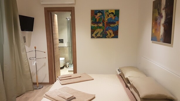Habitación de hotel con cama, mesita de noche, televisor de pantalla plana, un cuadro y zona de ducha.