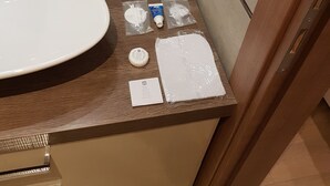 Un baño con un lavamanos grande, un espejo y artículos de tocador sobre la encimera.