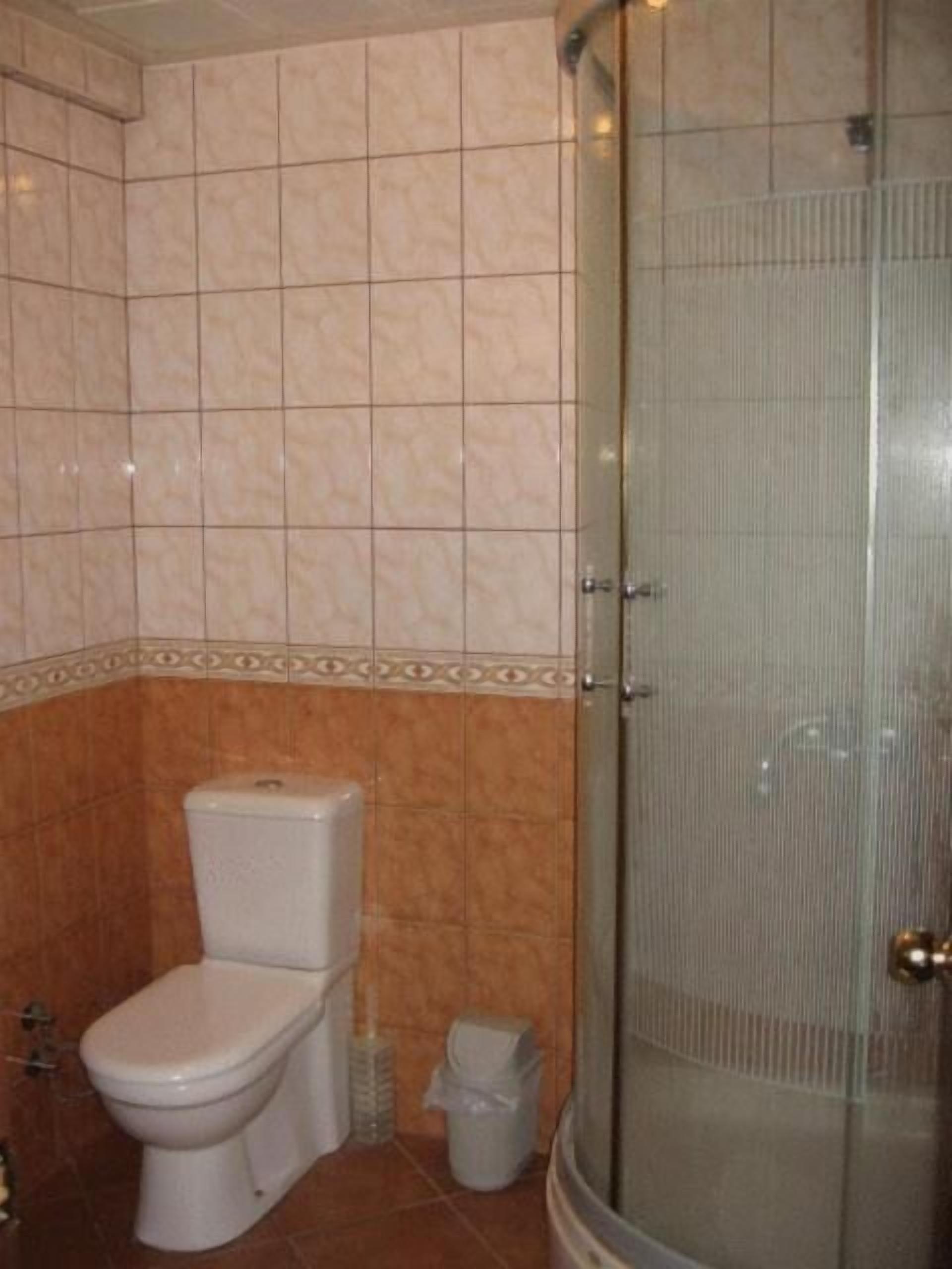 A bathroom with a toilet, a shower enclosure, and tiled walls.