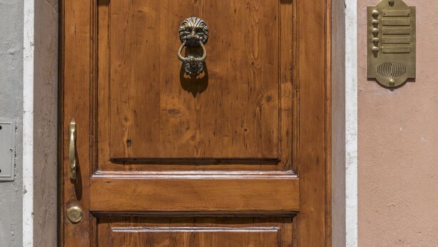 A wooden door with a brass knocker and a brass plaque with text.
