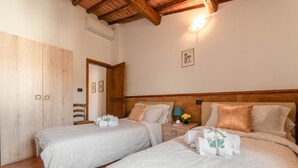 A bedroom with two beds, wooden wardrobe, and a small bedside table with a lamp.
