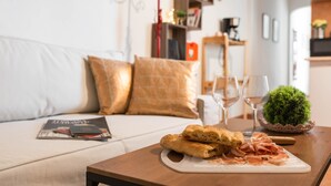A cozy living room with a wooden coffee table, a magazine, a plate of food, and a small potted plant.