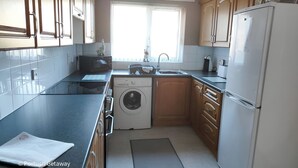 A compact kitchen with a washing machine, a sink, and a refrigerator. - Portrush Getaway – Family-Friendly Home Near Beaches & Town (Portrush)