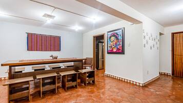 A dining area with a wooden table and benches, a colorful striped curtain, and a refrigerator in the background.