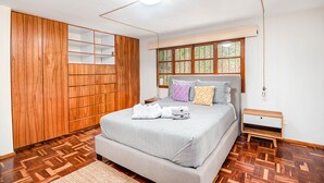 Un dormitorio con una cama grande, un armario de madera y una ventana con vista a árboles.