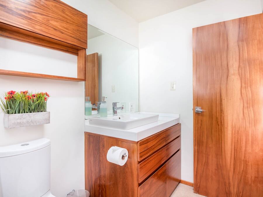 A modern bathroom with a wooden vanity, white sink, and a mirror above it.
