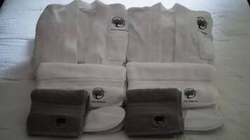 A neatly arranged set of white towels with a logo on them, placed on a bed.