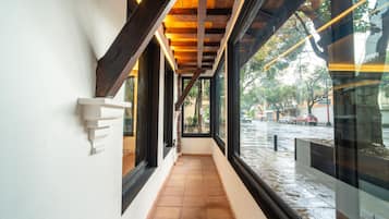 Un pasillo con suelo de baldosas, ventanas amplias y estructura de techo de madera.
