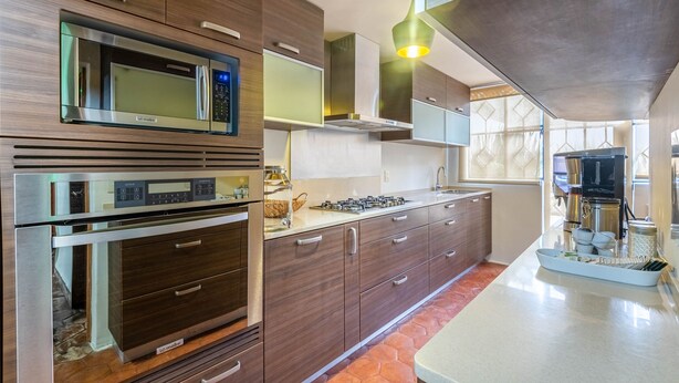 Una cocina moderna con electrodomésticos integrados, armarios de madera y una isla grande con fregadero.