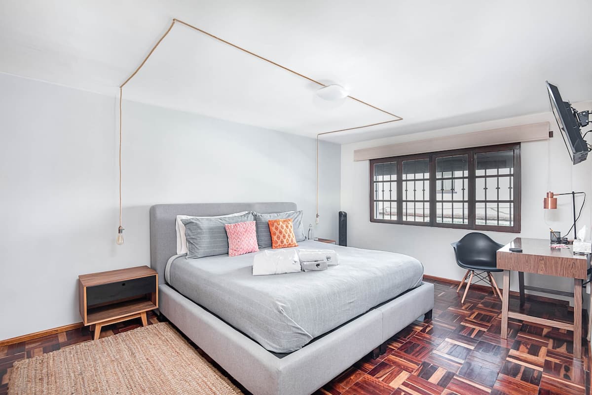 Een moderne slaapkamer met een bed, nachtkastje en bureau met stoel.