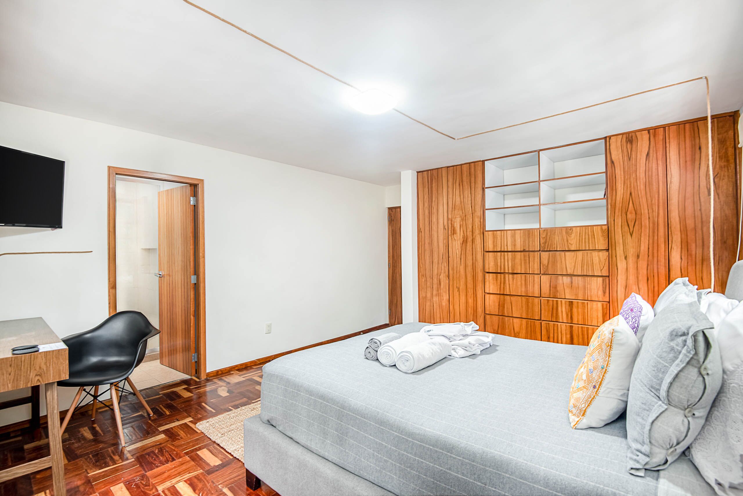 Un dormitorio con cama, escritorio, silla y televisión.