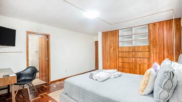 Un dormitorio con cama, escritorio, silla y televisión.