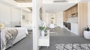 Une chambre à coucher moderne et bien éclairée, avec un grand lit, des tables de chevet et un miroir.