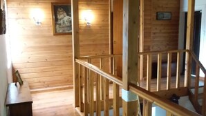 Ein Holzinnenraum mit einer Treppe, einem gerahmten Bild an der Wand und einem kleinen Tisch.
