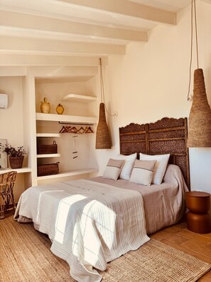 A bedroom with a bed, hanging lamps, shelves with decorative items, and a woven rug. - Nice house with pool in a quiet area. (San Francisco Javier)