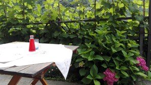 A wooden table with a white tablecloth, a red bottle, and a clear glass.