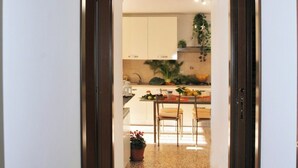 A narrow hallway leading to a kitchen with a dining area.