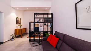 Un salon moderne avec un canapé foncé, une bibliothèque et un meuble en bois.