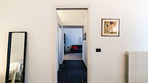 Un couloir avec un miroir, un radiateur et un tableau encadré accroché au mur.